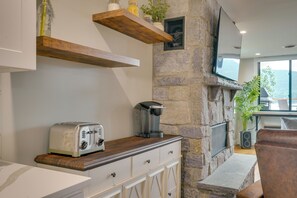 Une cuisine avec un mur en pierre, un four encastré, une machine à café et un grille-pain.