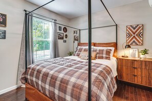 Ein Schlafzimmer mit einem Himmelbett, einem Nachttisch aus Holz und einer Wand mit gerahmten Bildern.