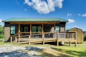 Eine Holzhütte mit Veranda und Terrasse, umgeben von einer Rasenfläche.