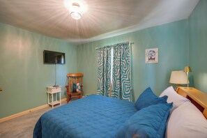Ein Schlafzimmer mit Bett, Sessel, Fernseher, Lampe und einem Bild an der Wand.