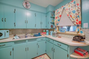 Een keuken met turquoise kastjes, een magnetron, een broodrooster en een vintage telefoon.