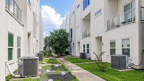 En bostadsbyggnad med flera våningar, luftkonditioneringsanläggningar och en välskött gräsmatta.
