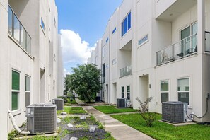 A residential building with multiple floors, air conditioning units, and a well-maintained lawn. - Walk to Astrodome! Houston Home w/ Balcony (Houston)