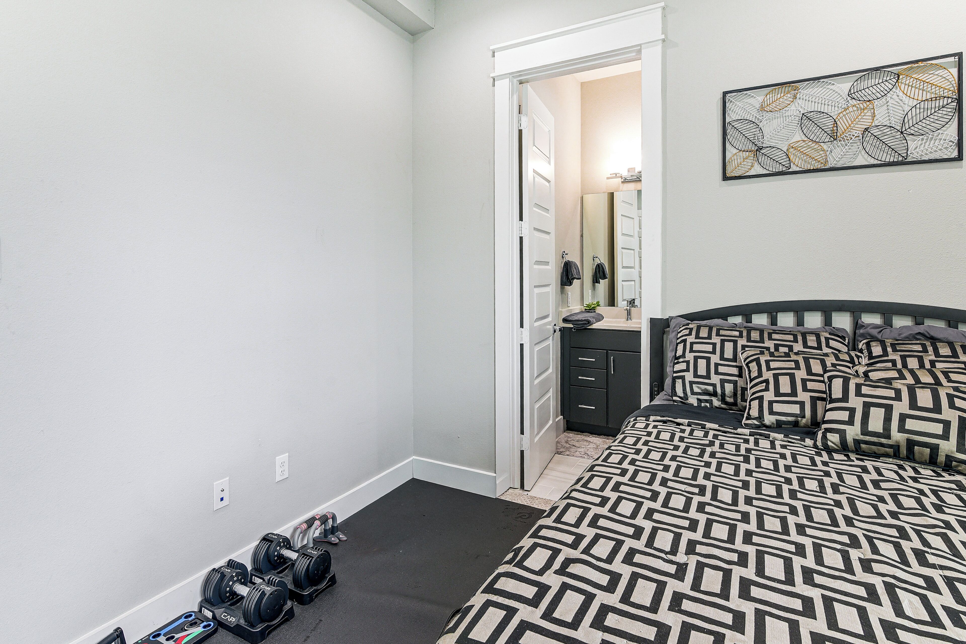Un dormitorio con cama, cómoda, espejo y puerta que da a otra habitación.