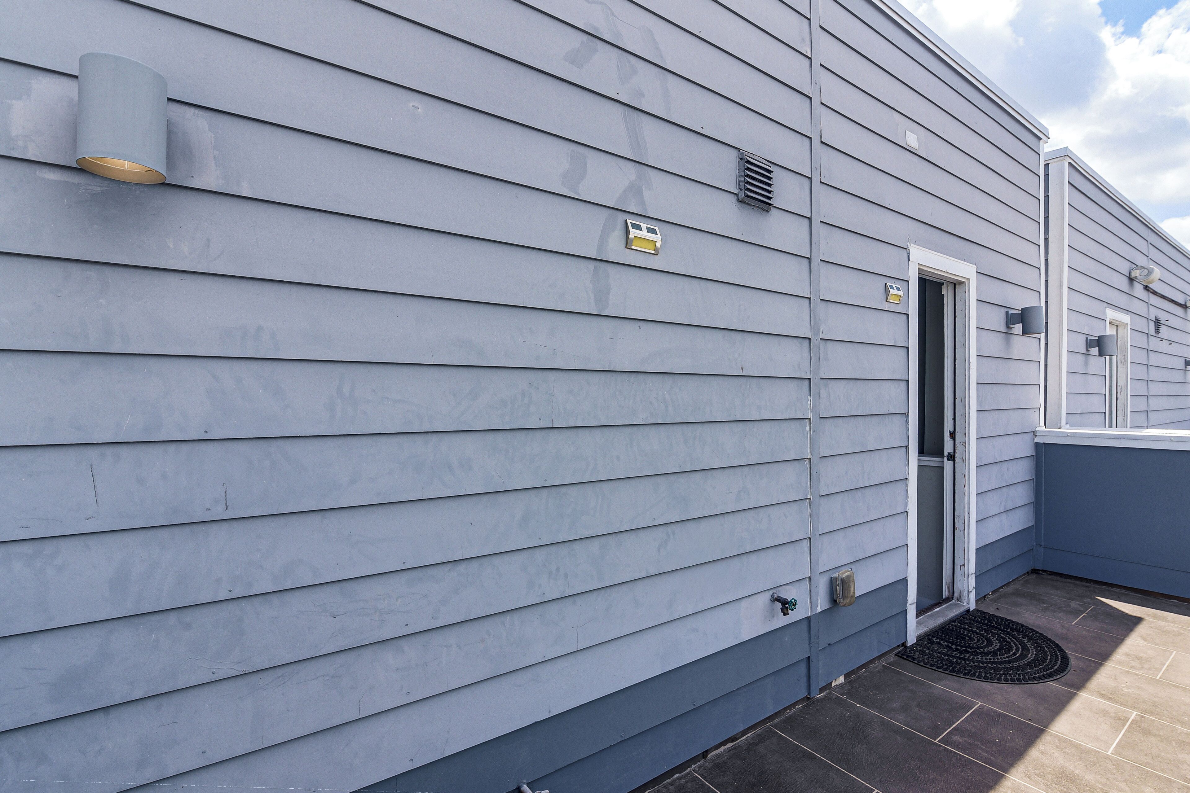 Un bâtiment avec un revêtement horizontal, une porte et une petite fenêtre.
