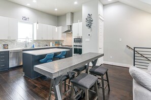 Een moderne keuken met een centraal eiland, barkrukken en een eettafel.