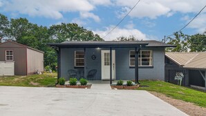 Uma casa térrea com varanda frontal, garagem e um pequeno jardim.