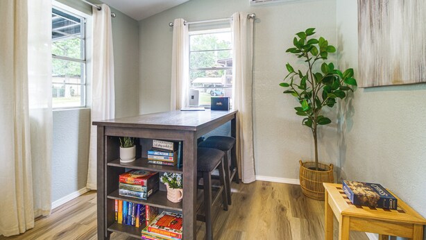 Um quarto com uma mesa de madeira, uma estante, um vaso de plantas e um tabuleiro de xadrez.