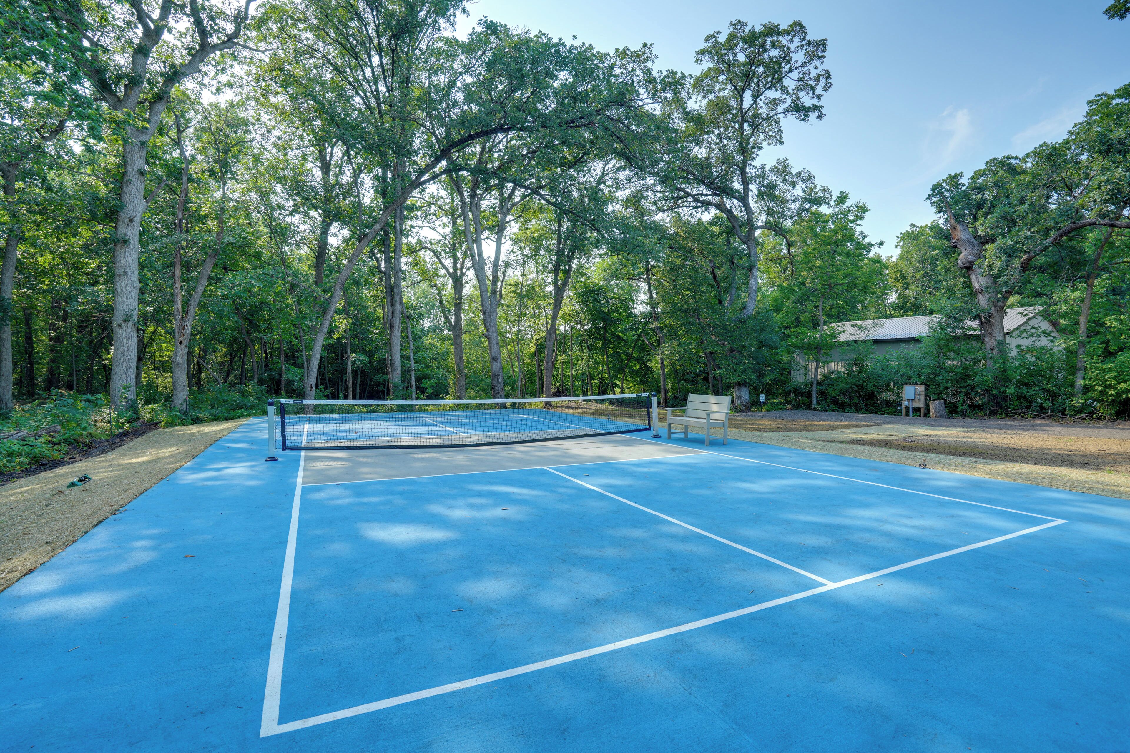 An outdoor tennis court surrounded by trees.