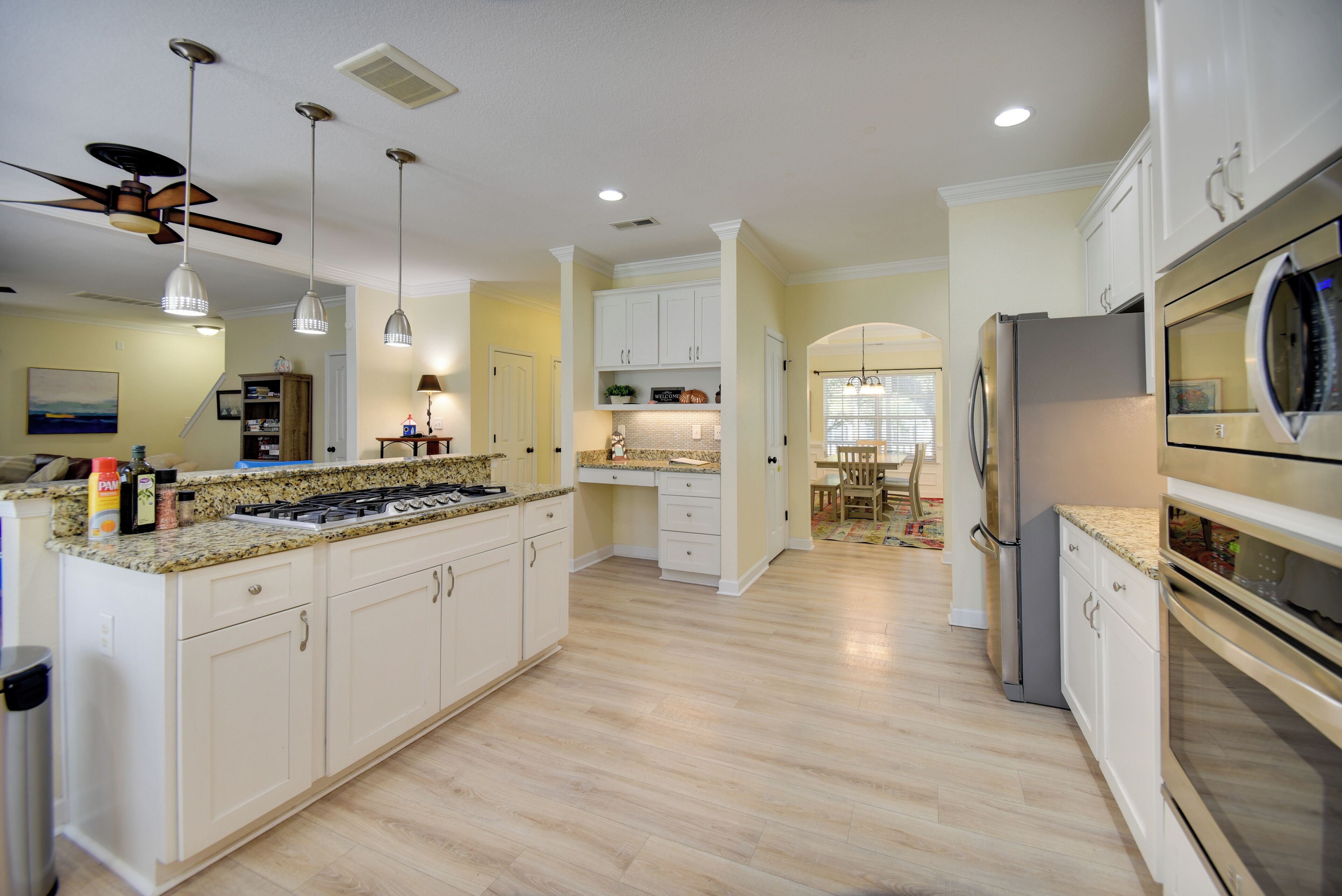 A modern kitchen with white cabinetry, a granite countertop, a built-in stove, and a refrigerator.