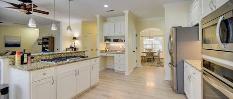A modern kitchen with white cabinetry, a granite countertop, a built-in stove, and a refrigerator.