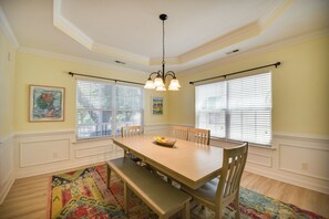 A dining room with a wooden table, chairs, a bench, a chandelier, and a colorful rug. - 1 Block to Beach + Private Patio in Norfolk (Norfolk)