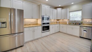 A modern kitchen with stainless steel appliances, white cabinetry, and a granite countertop. - 1 Block to Beach + Private Patio in Norfolk (Norfolk)