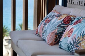 A bed with a floral-patterned pillow and a view of the ocean through a window. - Sea View 2 Bed & 2 Bath - Highly Rated, with Wi-Fi and Air Conditioning (Nice)