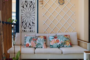 A sofa with floral cushions, a decorative white lattice, and a wall-mounted decorative plate. - Sea View 2 Bed & 2 Bath - Highly Rated, with Wi-Fi and Air Conditioning (Nice)