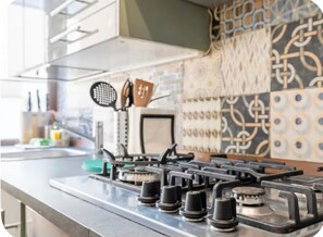 A kitchen with a gas stove, a microwave, and a patterned backsplash. - Keys of the Vatican by A Picture of Rome (Roma)