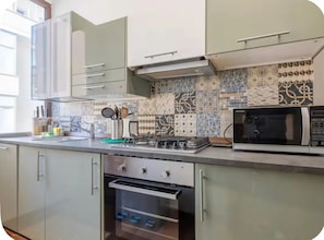 A kitchen with a microwave, stove, oven, and patterned backsplash. - Keys of the Vatican by A Picture of Rome (Roma)