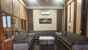 A modern living room with a sectional sofa, a coffee table, and a large window. - Rimjhim Water Kingdom & Resort (Mandar)