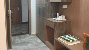 A compact room with a wooden wardrobe, a small desk, and a chair. A door leads to another room. - Rimjhim Water Kingdom & Resort (Mandar)