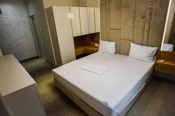 A hotel room with a bed, a wardrobe, a desk, and a nightstand. - Beach Vibe Hotel (Mamaia-Sat)