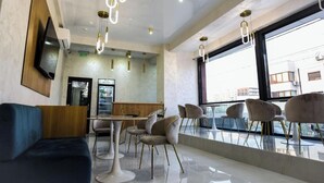 A modern interior with a dining area, seating, and a large window. - Beach Vibe Hotel  (Mamaia-Sat)