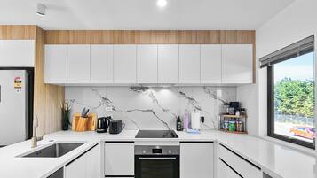 A modern kitchen with white cabinets, a marble backsplash, and a Bosch dishwasher.