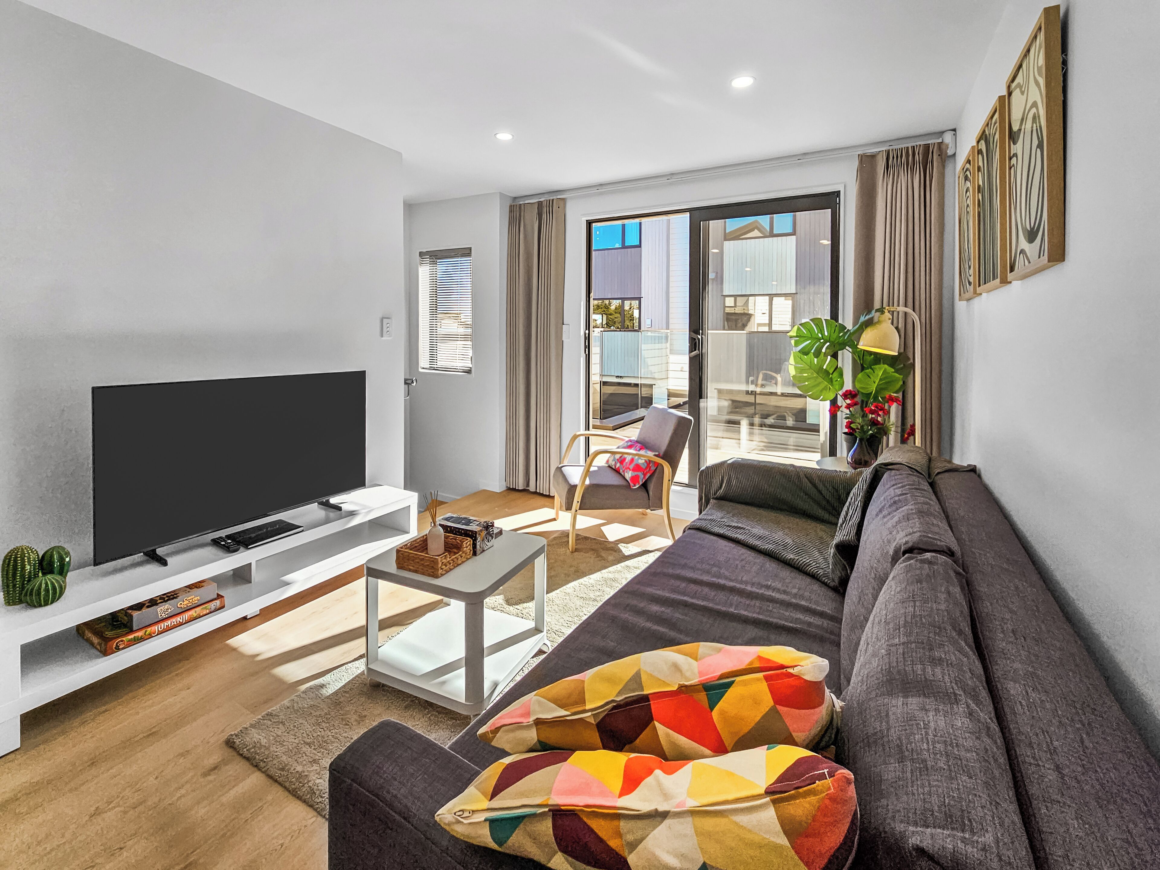A modern living room with a flat-screen TV, a sofa, a coffee table, and a chair.