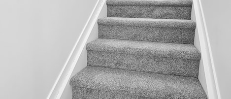 Una escalera con peldaños alfombrados y barandilla de metal.