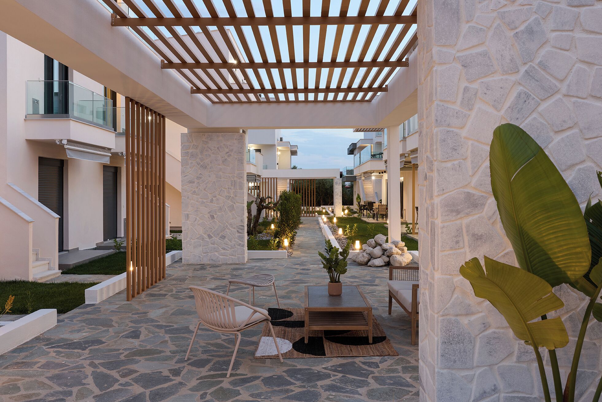 Eine moderne Terrassenanlage mit Steinplattenböden, Holzmöbeln und einer Steinwand.