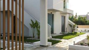 En moderne bygning med en belagt stenindgang, en træpergola og en velplejet have.