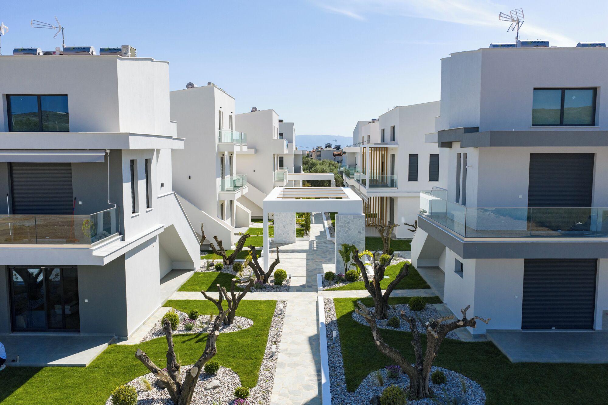 A modern residential complex with white buildings, balconies, and a central pathway.