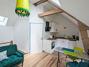 Eine Loft-Wohnung mit Küche, Essbereich und einem grünen Sofa.