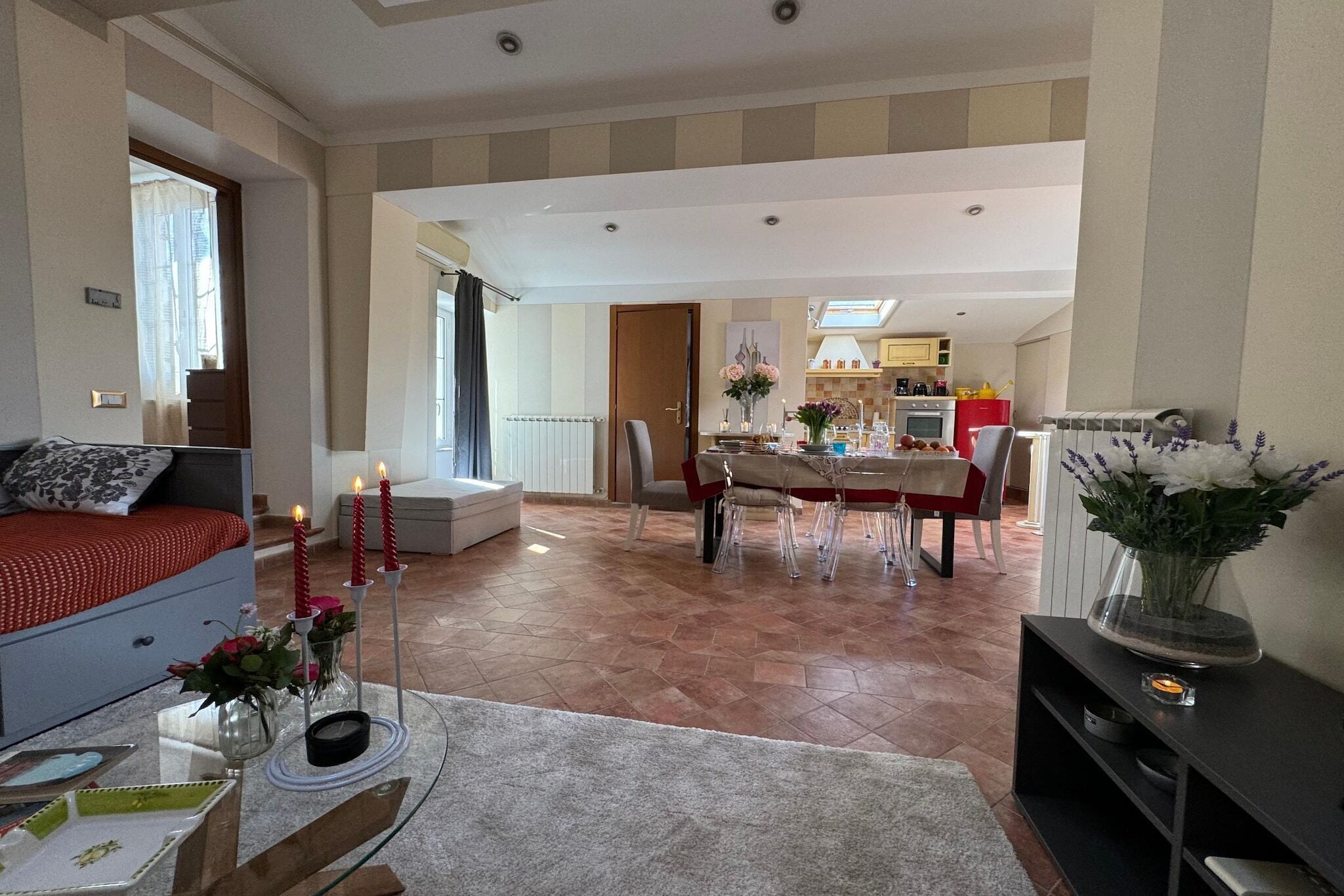 Amplia sala de estar con un sofá, una mesa de comedor y una cocina al fondo.