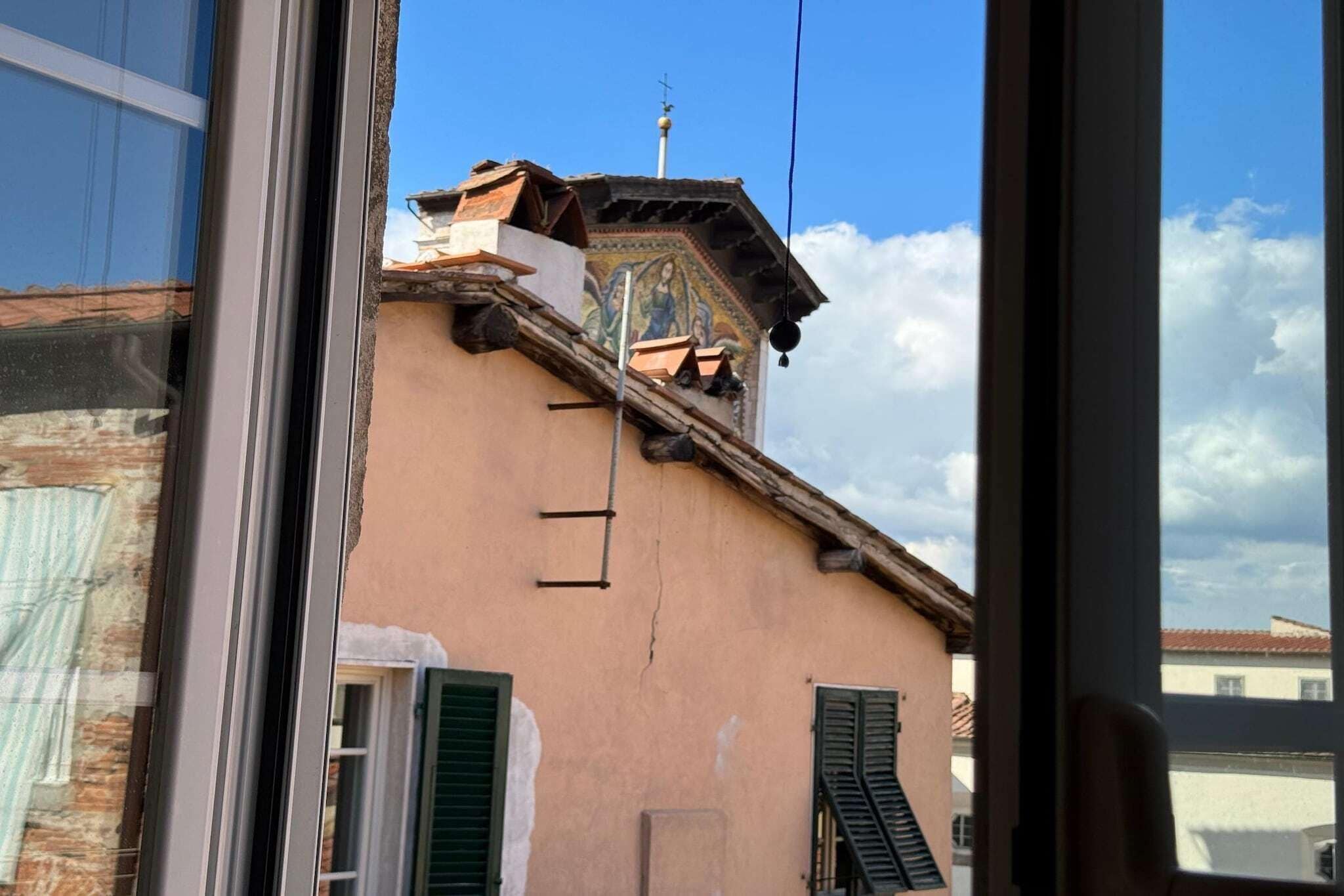Un edificio con techo inclinado, una chimenea visible y un balcón pequeño.