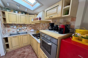A compact kitchen with a gas stove, oven, and coffee maker. - A Bright and Cozy Apartment with Stunning Views in the Heart of Lucca (Lucca)