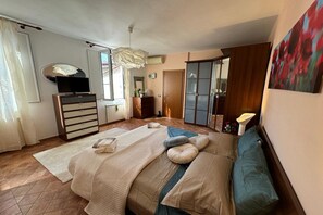 A bedroom with a bed, a dresser, a television, a wardrobe, and a painting on the wall. - A Bright and Cozy Apartment with Stunning Views in the Heart of Lucca (Lucca)