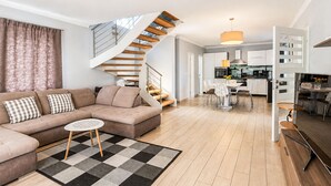 A modern living room with a beige sofa, a patterned rug, and a spiral staircase. - Stunning home in Porec (Porec)