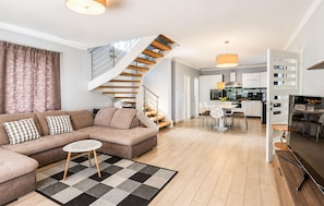Ein modernes Wohnzimmer mit einem beigen Sofa, einem gemusterten Teppich und einer Wendeltreppe.