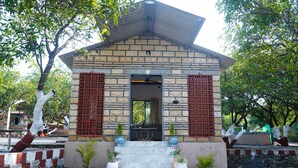 A small stone building with a tiled roof, a door, and a staircase leading up to it. - Kesar Villa (Bhojde)