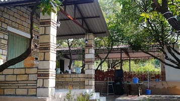A covered outdoor area with a brick structure, a metal roof, and a table with chairs.