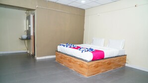 A bedroom with a bed, a nightstand, and a bathroom door. - Kesar Villa (Bhojde)