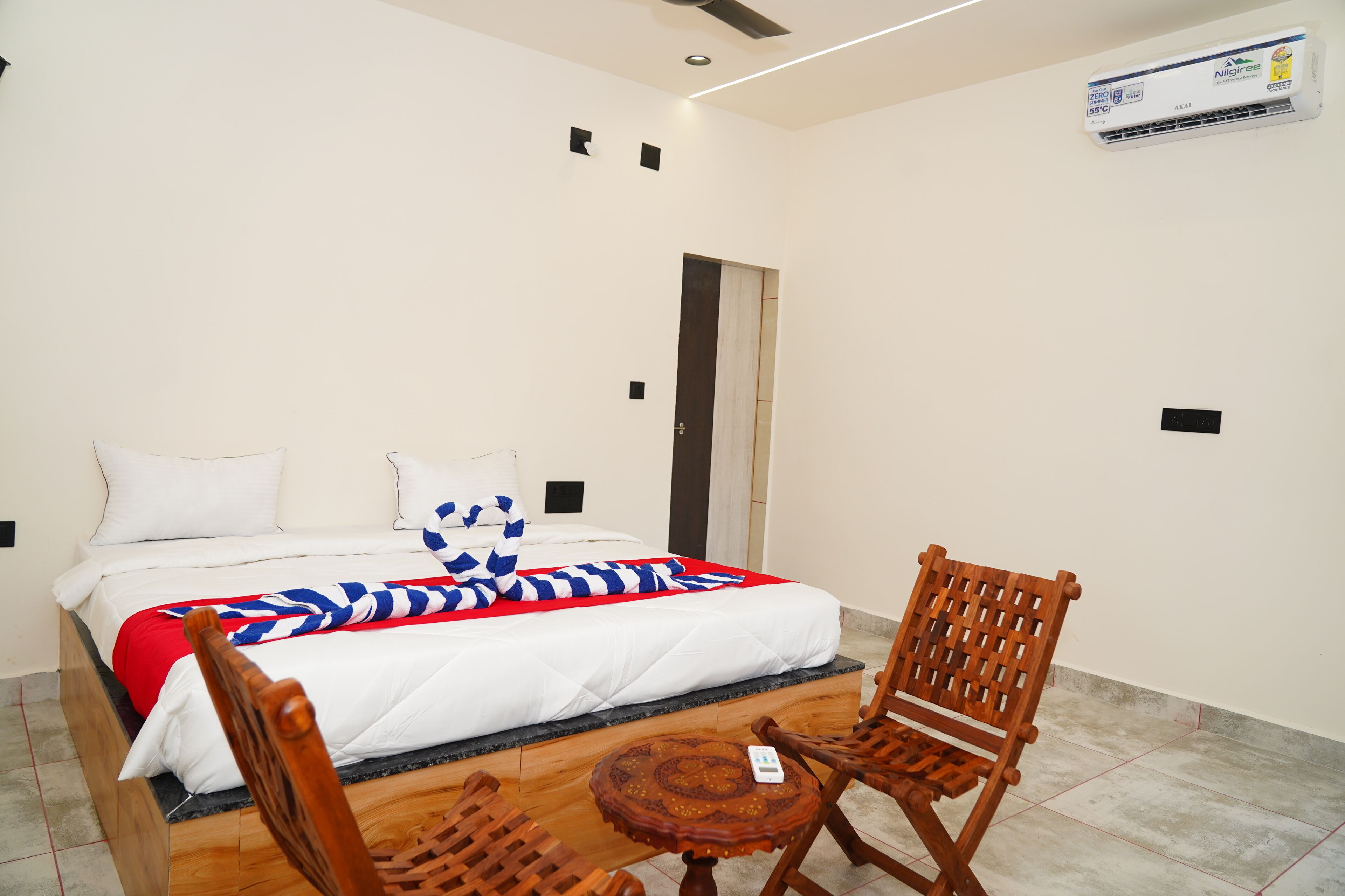 A hotel room with a bed, a wooden chair, a small table, and a ceiling fan.