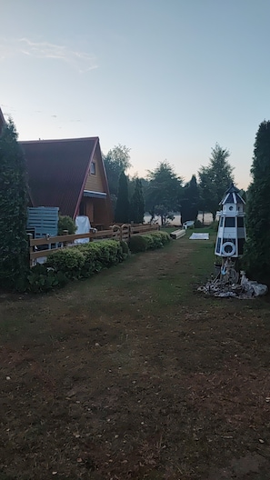 Una proprietà rurale con una casa in legno, un cortile recintato e una casetta per gli uccelli.