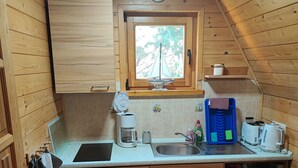 Une cuisine de taille réduite, avec des meubles de rangement en bois, une fenêtre et un petit évier.