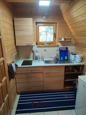 A compact kitchen with wooden cabinets, a window, and a small sink.