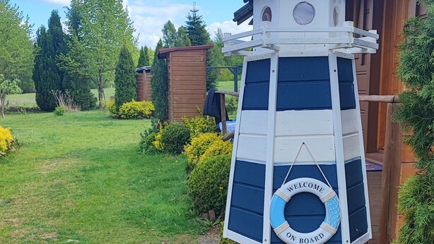 Une nichée à oiseaux ornée d’une pancarte sur laquelle on peut lire « Bienvenue à bord », entourée de rochers et d’une structure en bois.