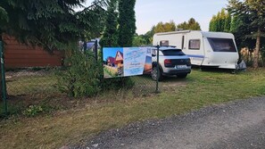 A campsite with a caravan and a car parked near a signboard.