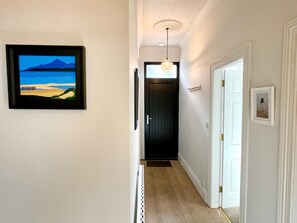 A hallway with a framed picture of a beach scene, a dark door, and a white door with a small picture on the wall. - The Cottage - Centre of Newcastle Co.Down (Newcastle)