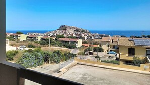 Eine Küstenstadt mit einer markanten Struktur auf einem Hügel, vermutlich ein Schloss oder eine Festung, mit Blick auf das Meer.