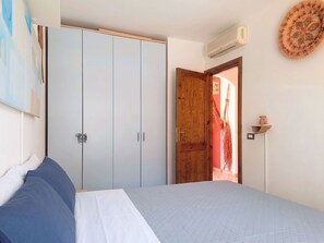 Ein Schlafzimmer mit einem Bett, einem Kleiderschrank und einer Tür zu einem anderen Raum.